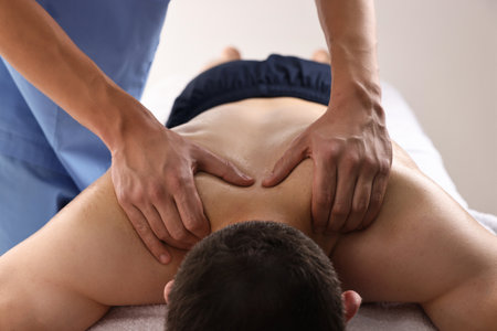 Professional physiotherapist doing neck massage for his client indoors, closeupの写真素材