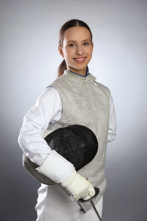 Smiling fencer with epee on gray background