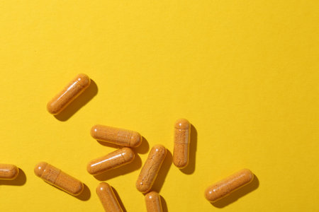 Many turmeric capsules on yellow background, flat lay. Space for textの写真素材