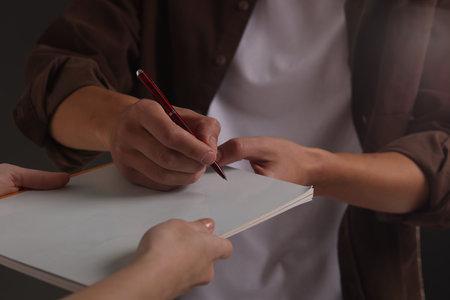 Man signing autograph in notebook, closeup viewの写真素材
