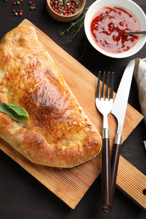 Delicious fresh calzone pizza served on wooden table, flat lay