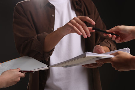 Man signing autograph in notebook on black background, closeupの写真素材