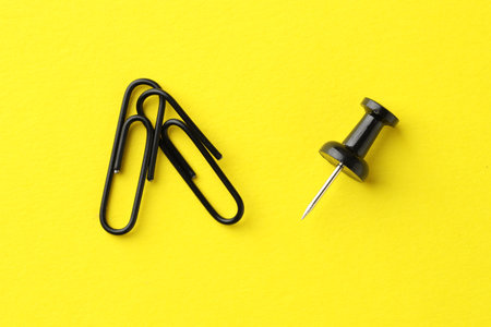 Paper clips and pin on yellow background, top viewの写真素材