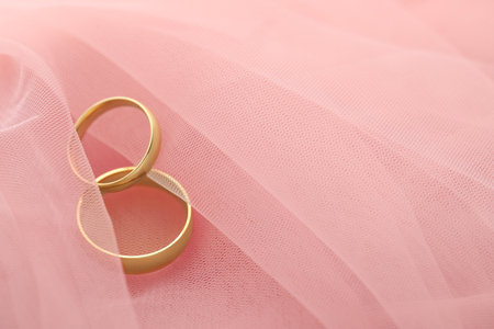 Beautiful golden wedding rings on pink fabric, space for textの写真素材