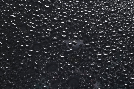 Water drops on dark gray glass surface, top viewの写真素材
