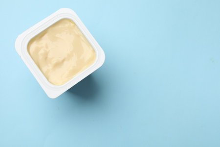 Delicious yogurt in plastic cup on light blue background, top view. Space for textの写真素材