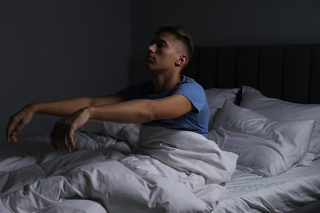 Young man suffering from sleepwalking on bed at homeの写真素材