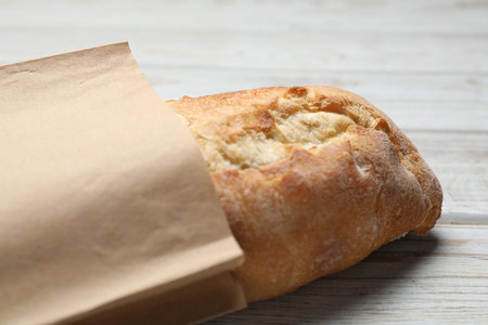 Paper bag with fresh baguette on wooden table, closeupの写真素材