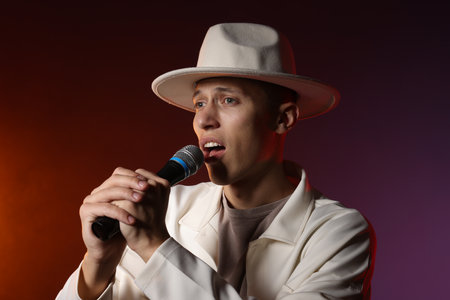 Talented singer performing on dark background with color lightsの写真素材
