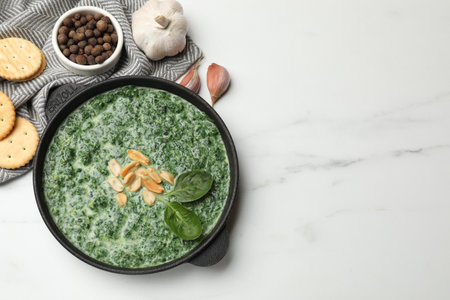 Delicious spinach sauce with peanuts and crackers on white table, flat lay. Space for text
