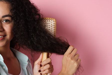 Woman brushing her curly hair on pink background, closeupの写真素材