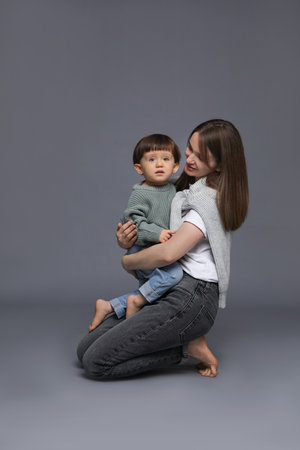 Mother hugging her little son on gray background. Space for textの写真素材