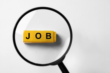 Job search concept. Word made with cubes on white background, view through magnifying glassの写真素材