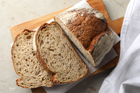 Cut loaf of fresh bread on table, top view