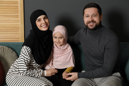 Happy Muslim family sitting on sofa at homeの写真素材