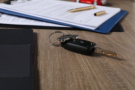 Car key and purchase agreement on wooden table, closeup. Buying autoの写真素材