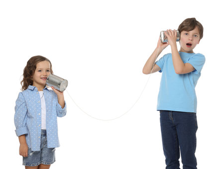 Boy and girl talking on tin can telephone against white backgroundの写真素材