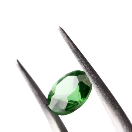 Tweezers with shiny green gemstone isolated on whiteの写真素材