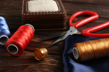 Different sewing supplies on wooden table, closeup