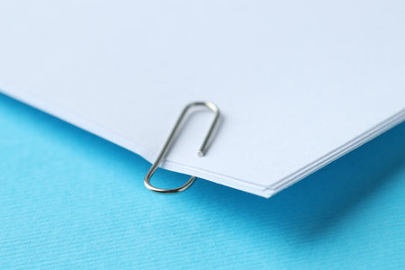 Paper notes with clip on light blue backgroundの写真素材