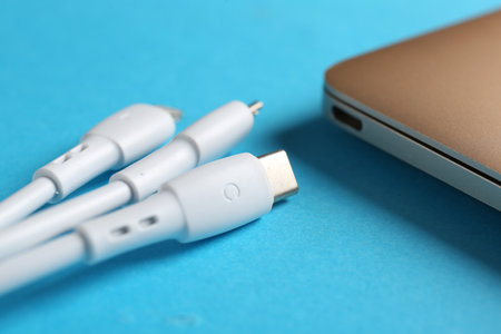 USB charge cables and laptop on light blue background, closeupの写真素材