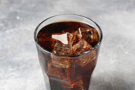 Refreshing cola with ice cubes in glass on light table, closeupの写真素材