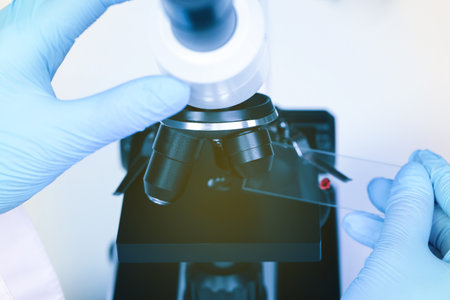 Scientist examining sample on slide under microscope, closeupの写真素材