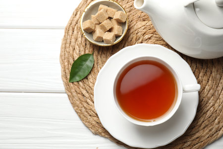 Aromatic black tea and brown sugar cubes on white wooden table, top view. Space for textの写真素材