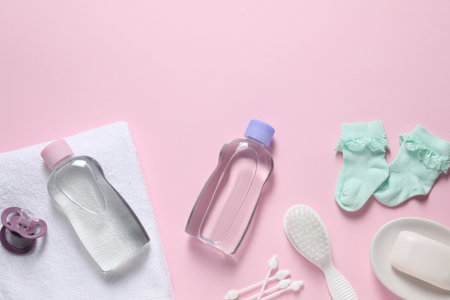 Baby oil and bath accessories on light pink background, flat lay. Space for textの写真素材
