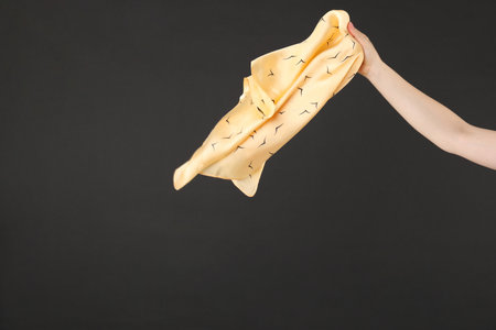 Woman holding beautiful handkerchief on black background, closeup. Space for textの写真素材