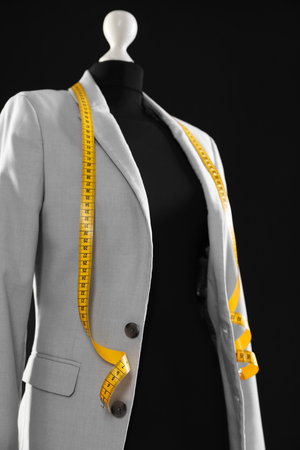 Female mannequin with gray jacket and measuring tape on black background, closeupの写真素材