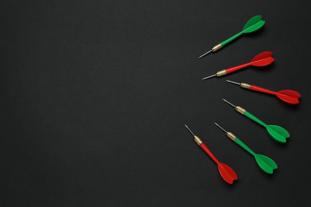 Colorful dart arrows on black background, flat lay. Space for textの写真素材