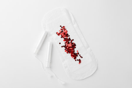 Menstrual pad with red sequins and tampons on white background, top viewの写真素材