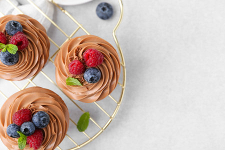 Tasty cupcakes with chocolate cream and berries on white table, flat lay. Space for textの写真素材