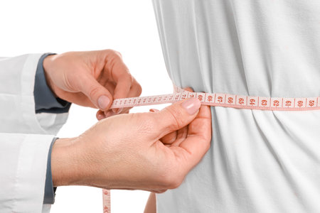 Weight loss. Nutritionist measuring patient's waist with tape on white background, closeupの写真素材