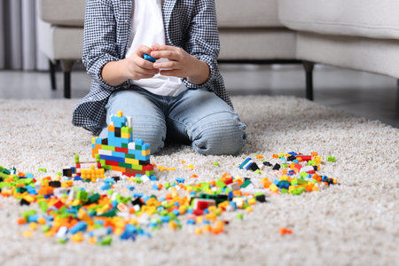 Cute boy playing with building blocks on floor at home, closeupの写真素材