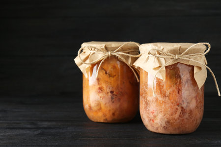 Canned meat in glass jars on wooden table, space for textの写真素材