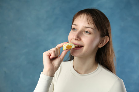 Beautiful woman eating tasty food on blurred blue background