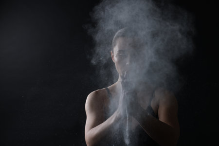 Woman clapping hands with powder before training on black background, space for textの写真素材