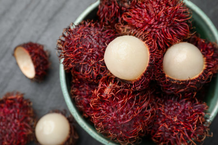 Ripe rambutans in bowl on black table, top viewの写真素材