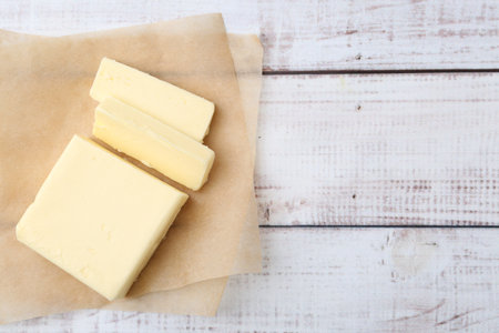 Cut block of fresh butter on white wooden table, top view. Space for textの写真素材