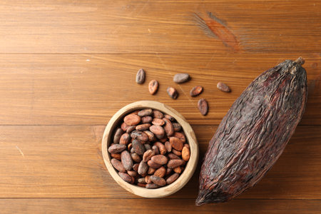 Cocoa pod and beans on wooden table, flat lay. Space for textの写真素材
