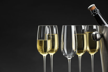 Bottle of sparkling wine in cooler bucket and glasses against gray background, closeupの写真素材