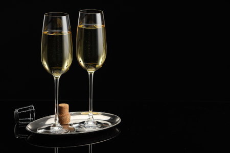 Glasses of sparkling wine on black mirror surface.の写真素材
