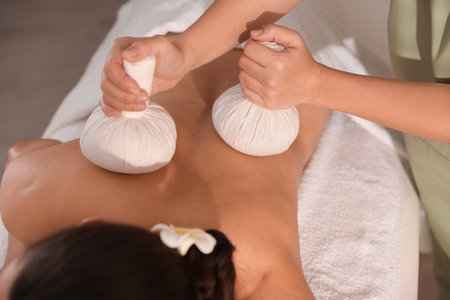 Woman receiving back massage with herbal bags in spa salon, closeupの写真素材
