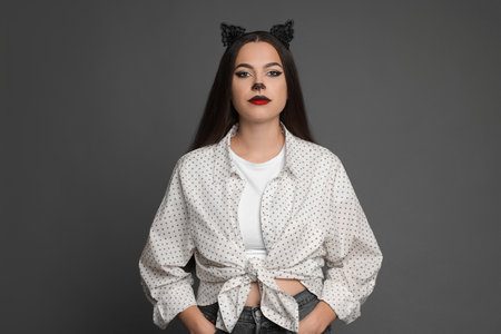 Attractive woman with cat makeup and ears on grey backgroundの写真素材