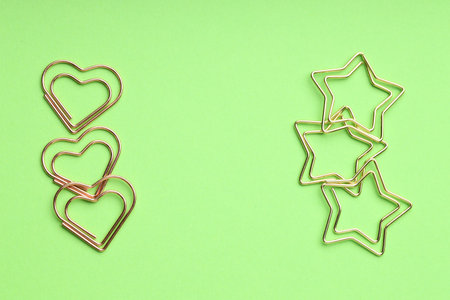 Different paper clips on green background, flat lay. Space for text