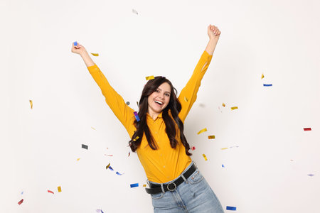 Happy woman under falling confetti on white background. Surprise partyの写真素材