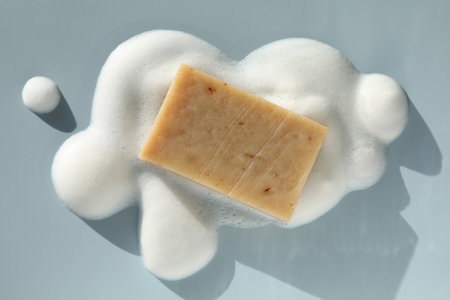 Soap bar with foam on grayish blue background, top viewの写真素材