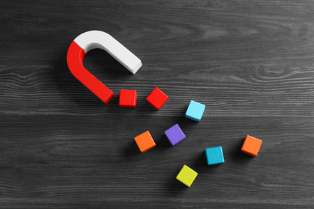 Magnet attracting with colorful cubes on wooden table, flat layの写真素材